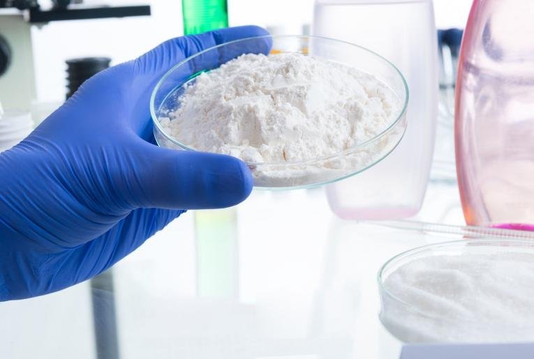 Gloved hand holding a sample of fine white powder
